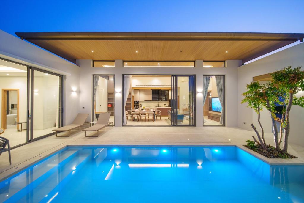 Villa pool terrace at dusk with dining and living area glowing through glass doors